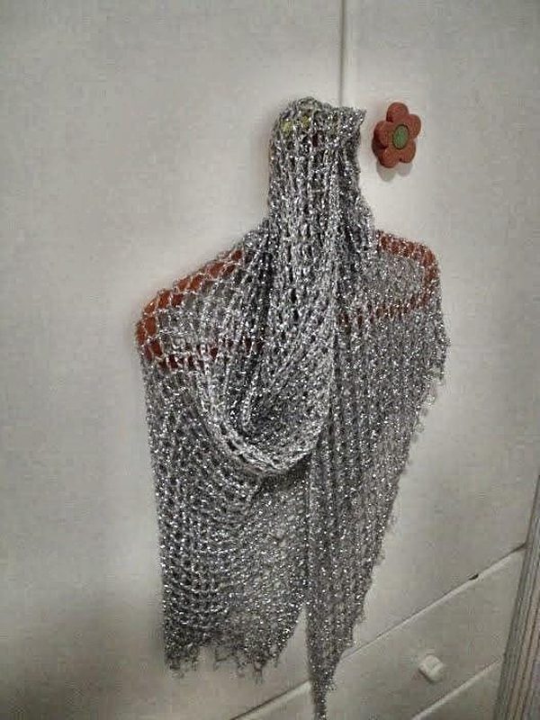 Silver beaded lurex shawl hanging on a red hanger against a white door, folded into a soft cowl drape.