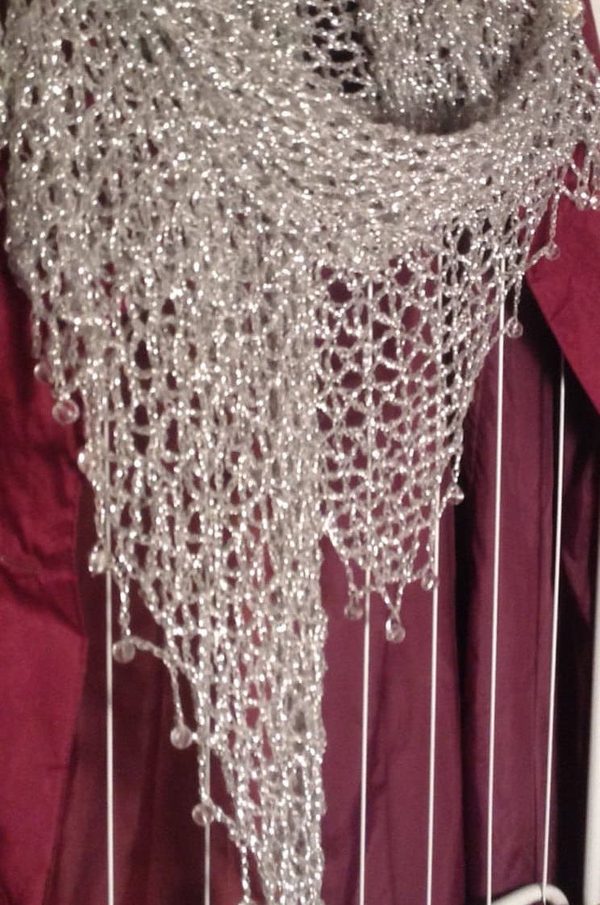 Close-up of the silver lurex shawl over a burgundy garment, showing the beaded edge and openwork crochet.